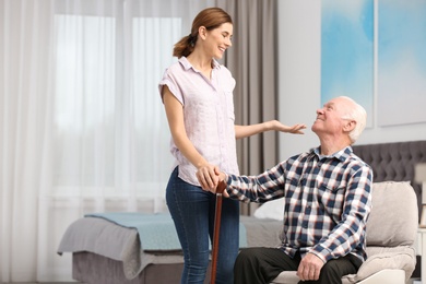 Elderly man with female caregiver at home. Space for text