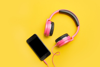 Photo of Stylish headphones and modern phone on color background, flat lay. Space for text