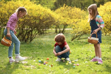 Photo of Easter celebration. Cute little children hunting eggs outdoors