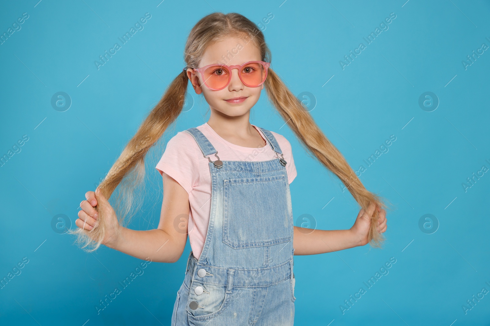 Photo of Girl in pink sunglasses on light blue background