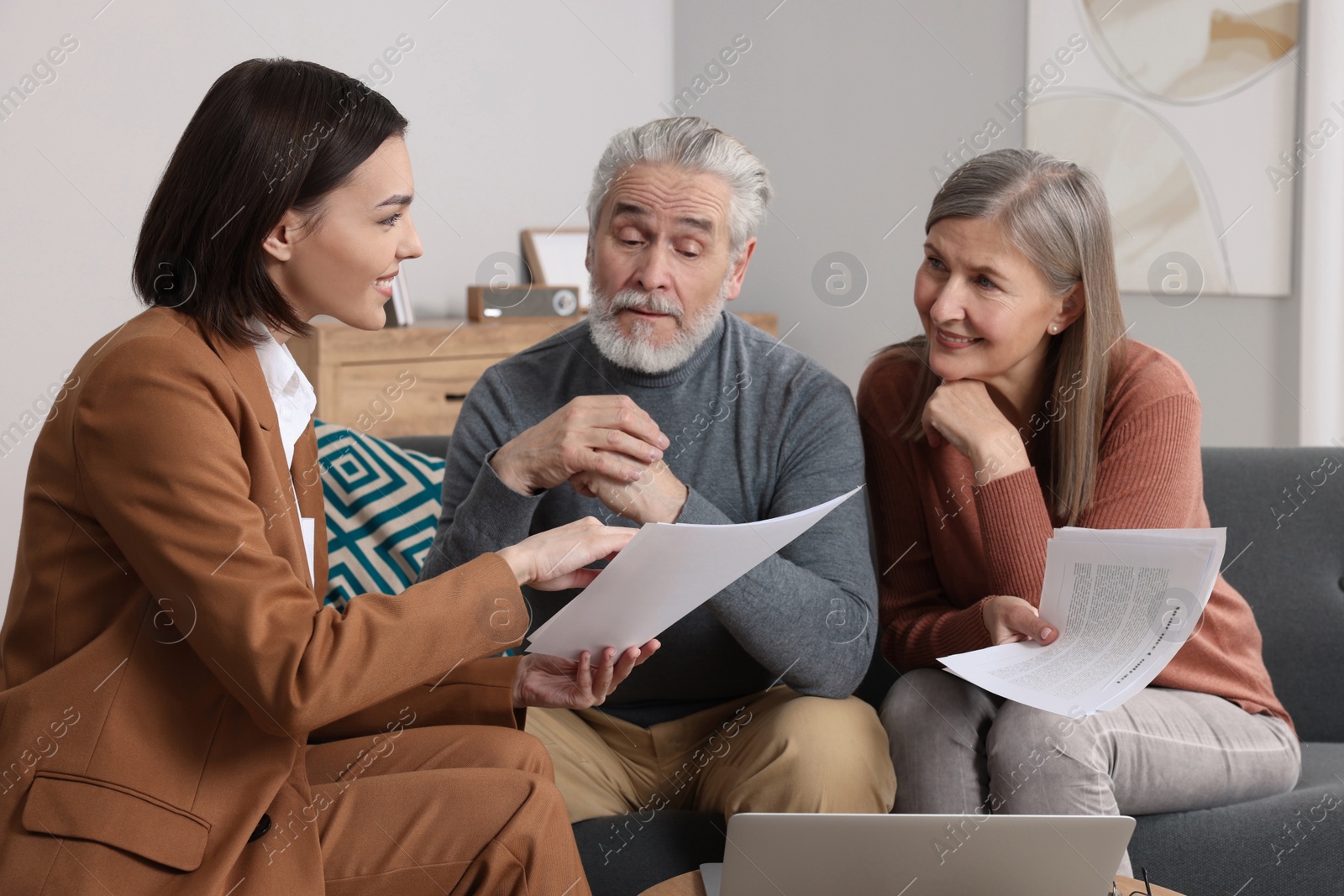 Photo of Insurance agent consulting elderly couple about pension plan in room