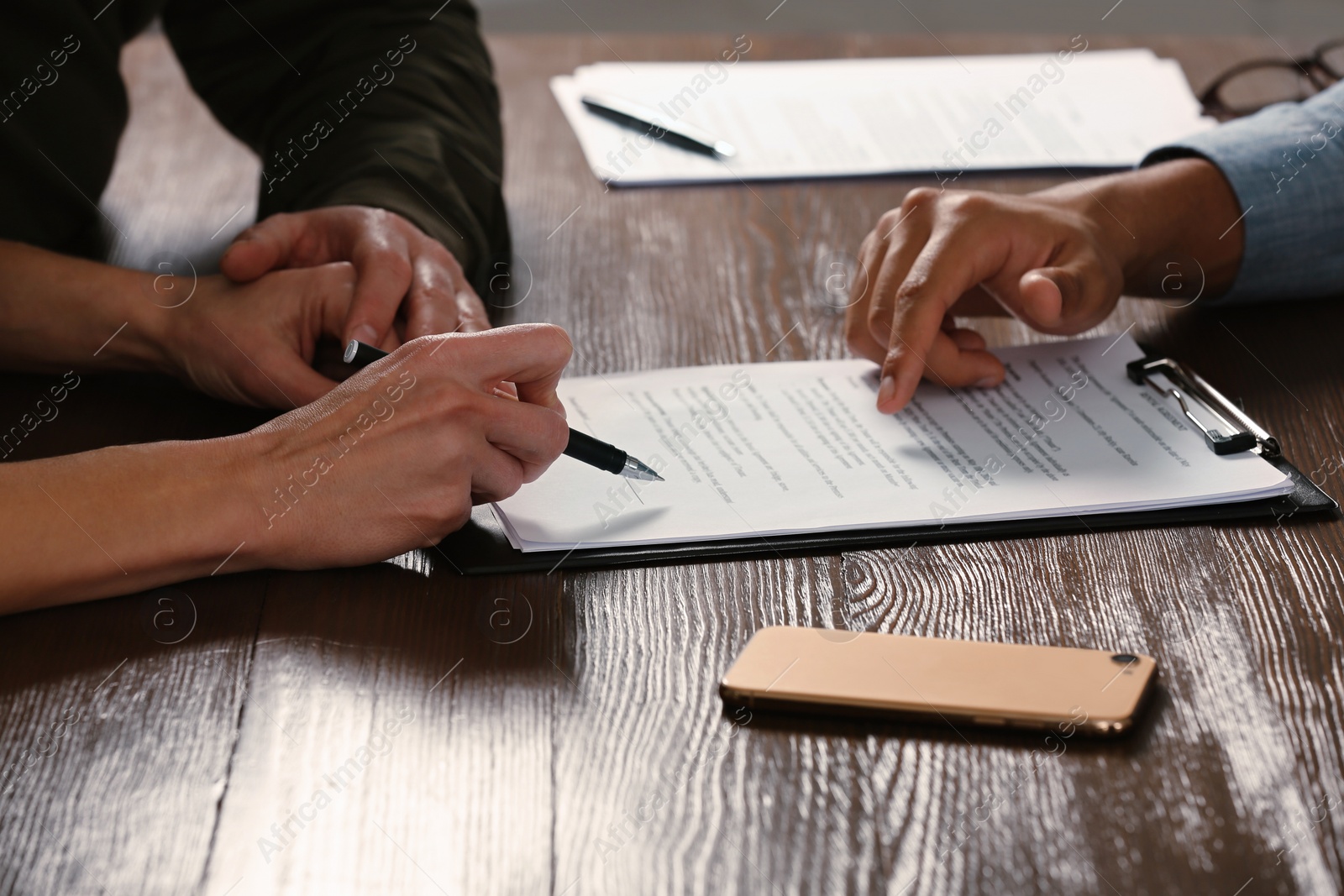 Photo of Notary working with couple at wooden table, closeup