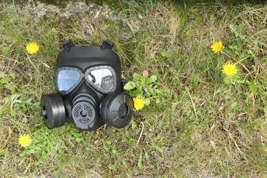 Photo of One gas mask on green grass outdoors, top view. Space for text