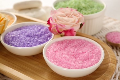 Photo of Bowls with different sea salt and beautiful rose on wicker mat, closeup