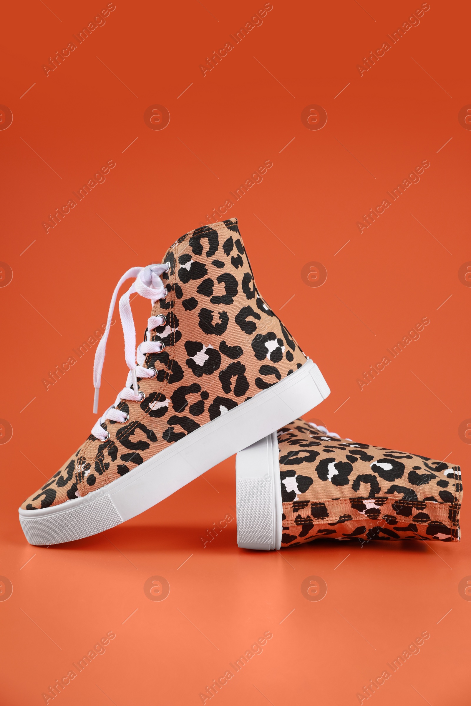 Photo of Pair of classic old school sneakers on terracotta background