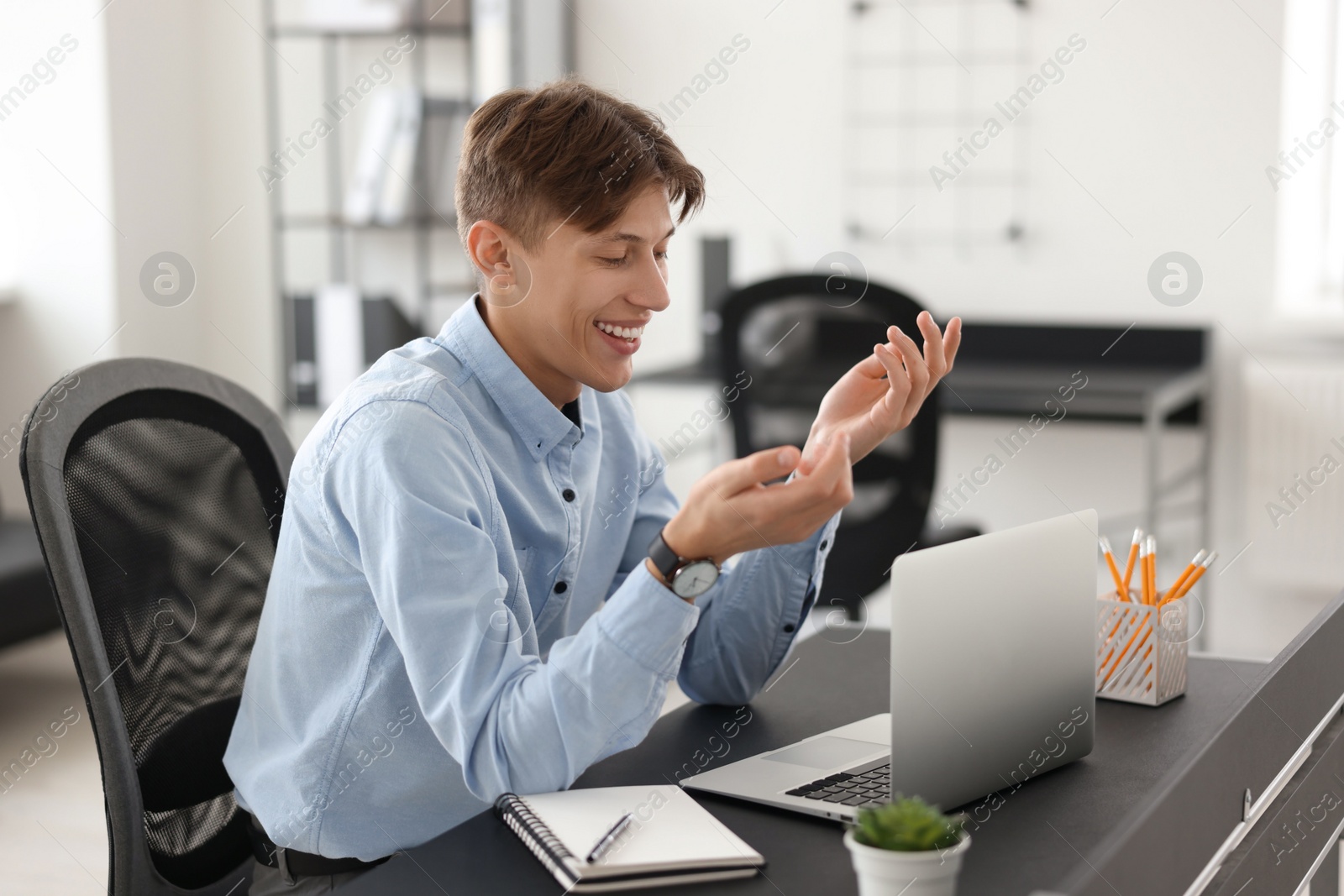 Photo of Man using video chat during webinar at table in office