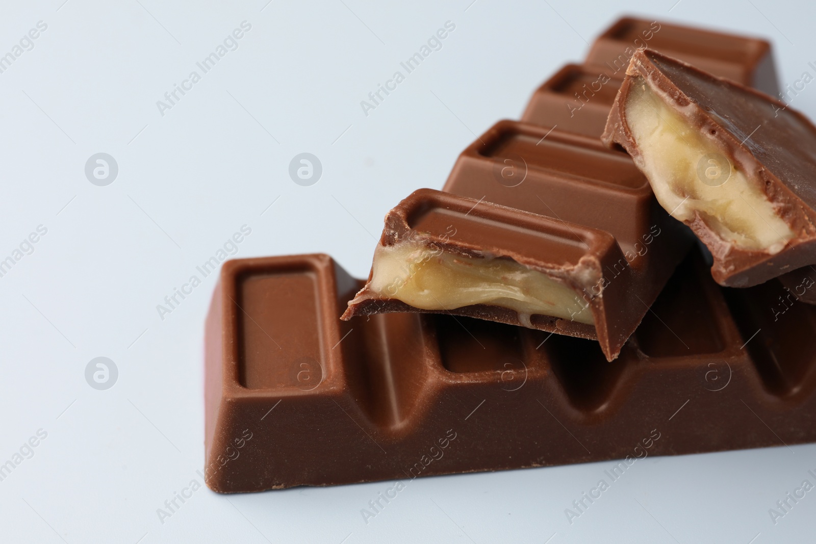 Photo of Delicious chocolate bars on light blue background, closeup
