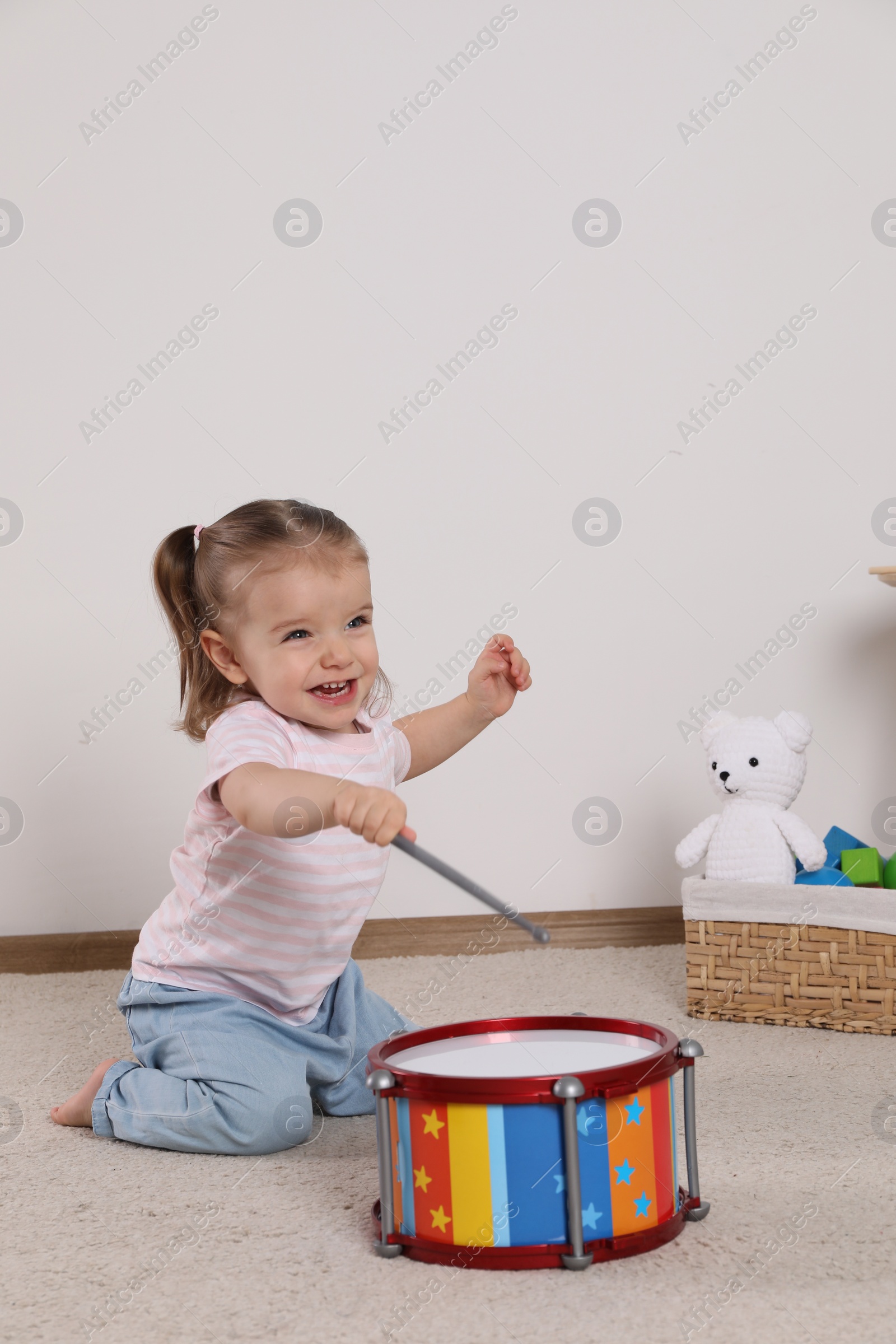 Photo of Cute little girl playing with drum and drumsticks at home