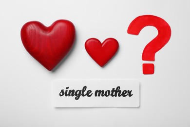 Photo of Being single mother concept. Decorative hearts and question mark on white background, flat lay