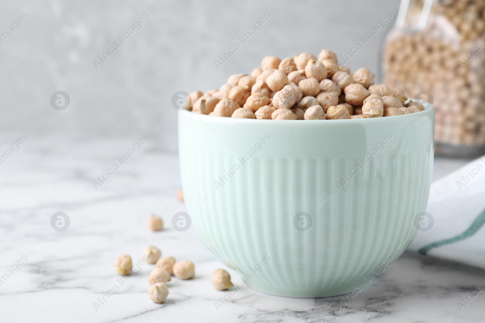 Photo of Chickpeas in bowl on white marble table, space for text