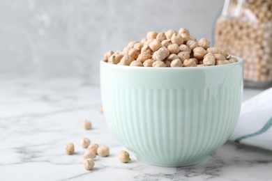 Photo of Chickpeas in bowl on white marble table, space for text