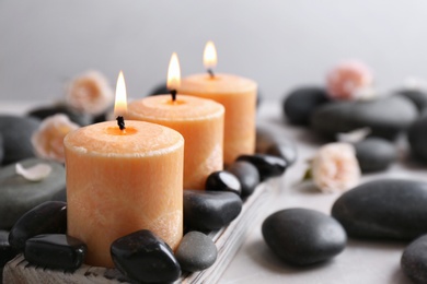 Photo of Beautiful composition with candles and spa stones on table. Space for text