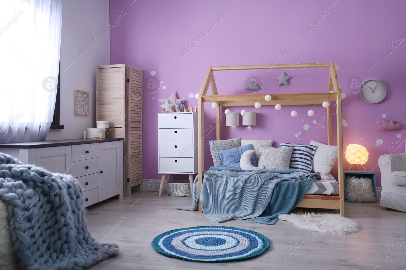 Photo of Child's room interior with comfortable bed and garland