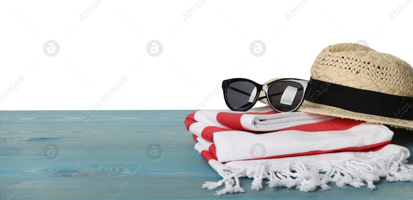 Photo of Beach towel, straw hat and sunglasses on light blue wooden surface against white background. Space for text