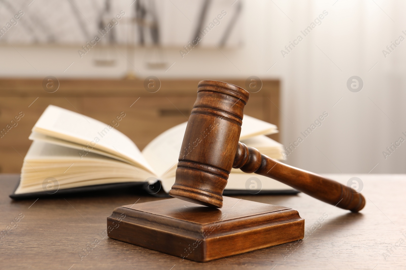 Photo of Wooden gavel and sound block on table indoors, closeup