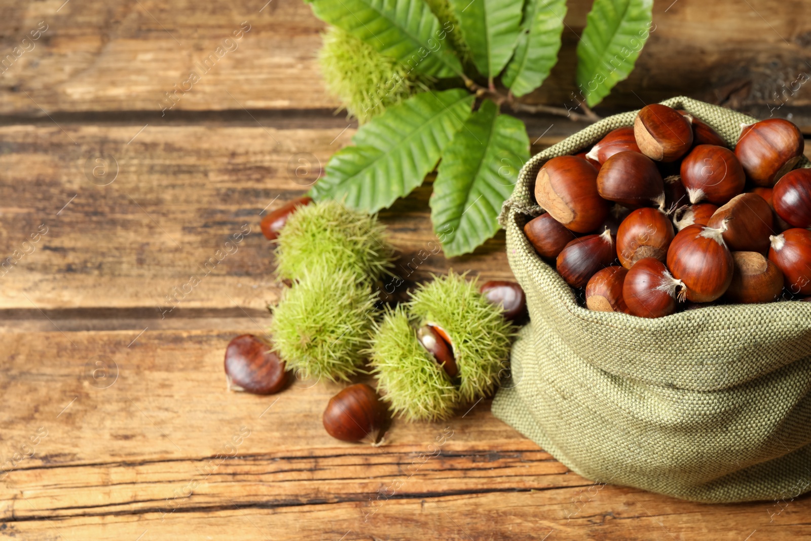 Photo of Fresh sweet edible chestnuts on wooden table, above view. Space for text