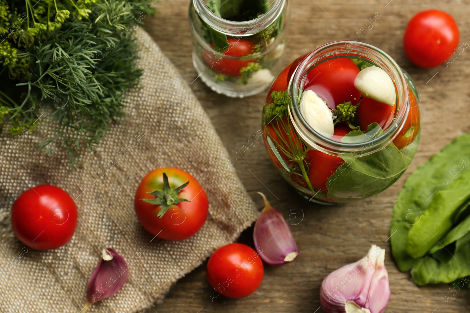 Photo of Glass jars, fresh vegetables and herbs on wooden table, flat lay. Pickling recipe