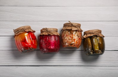 Jars with pickled vegetables on white wooden table, flat lay