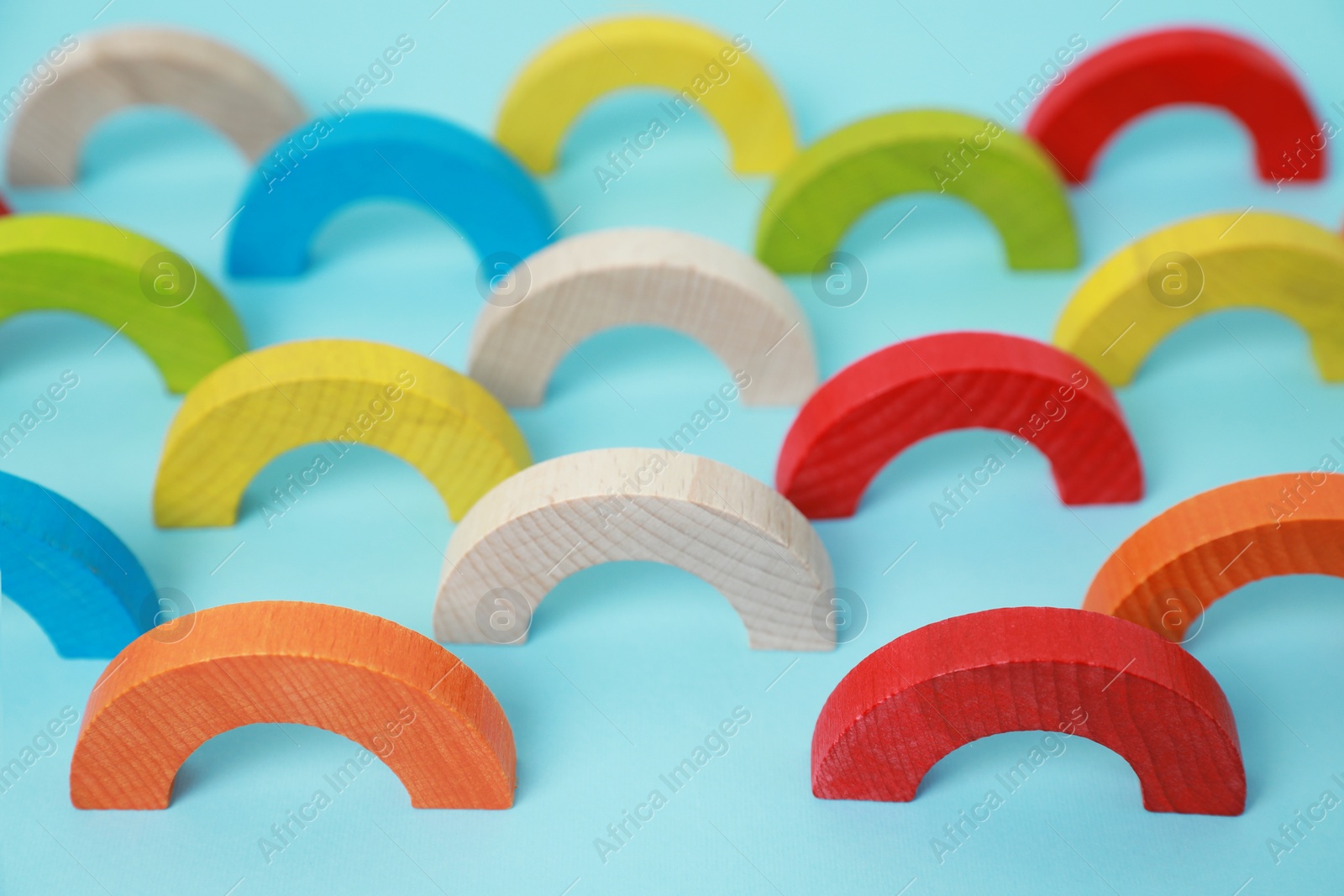 Photo of Colorful wooden pieces of playing set on light blue background. Educational toy for motor skills development