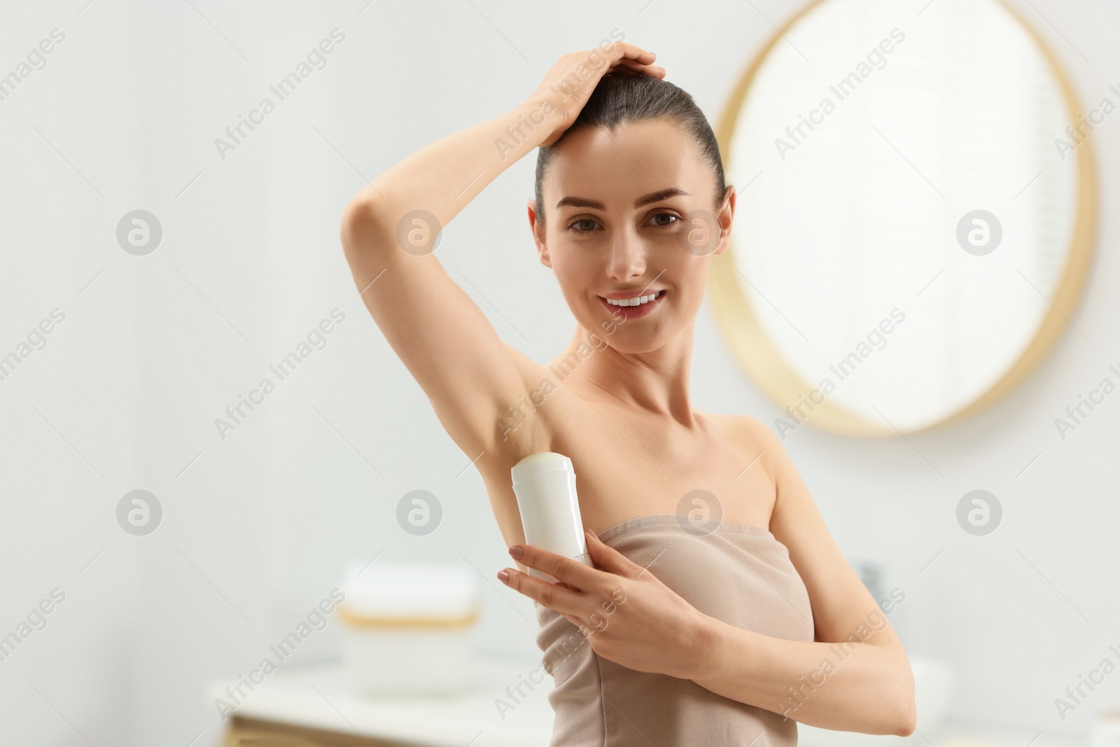 Photo of Beautiful woman applying deodorant in bathroom, space for text