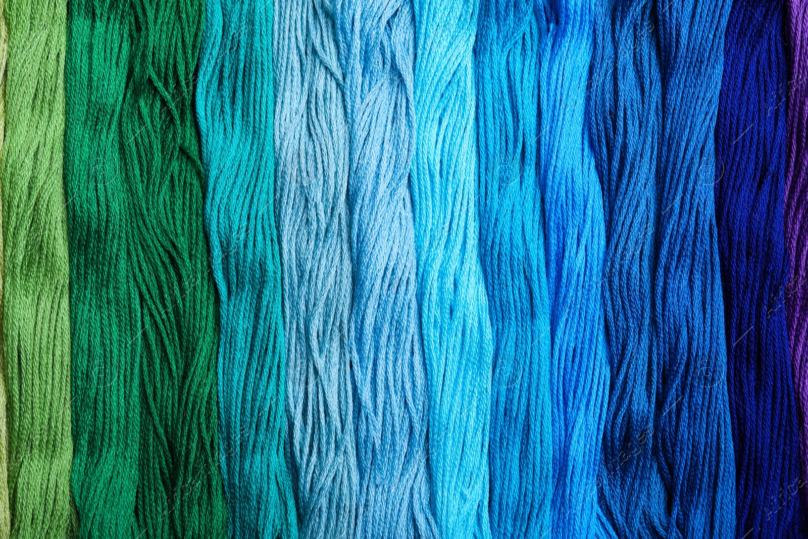 Photo of Different colorful embroidery threads as background, top view