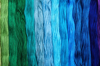 Photo of Different colorful embroidery threads as background, top view