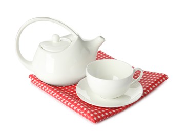 Photo of Ceramic cup with saucer, teapot and red checkered tablecloth isolated on white