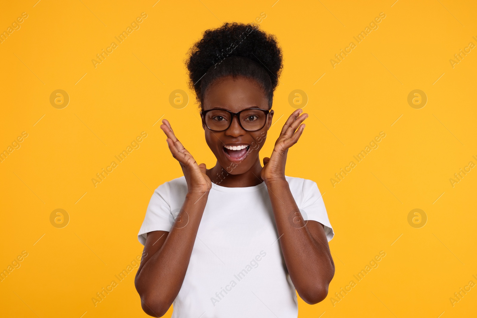 Photo of Portrait of happy young woman in eyeglasses on orange background