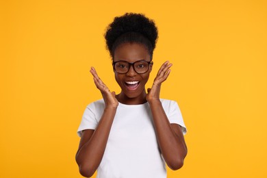 Photo of Portrait of happy young woman in eyeglasses on orange background