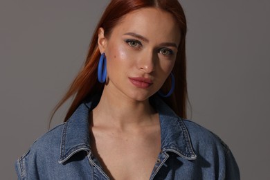 Beautiful young woman in denim jacket on gray background