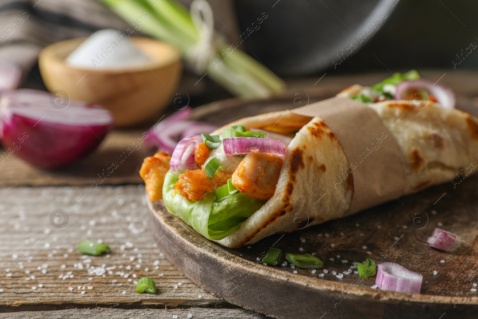 Photo of Delicious pita wrap with meat and vegetables on wooden table, closeup. Space for text
