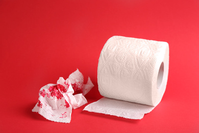 Photo of Sheets of toilet paper with blood on red background. Hemorrhoid problems