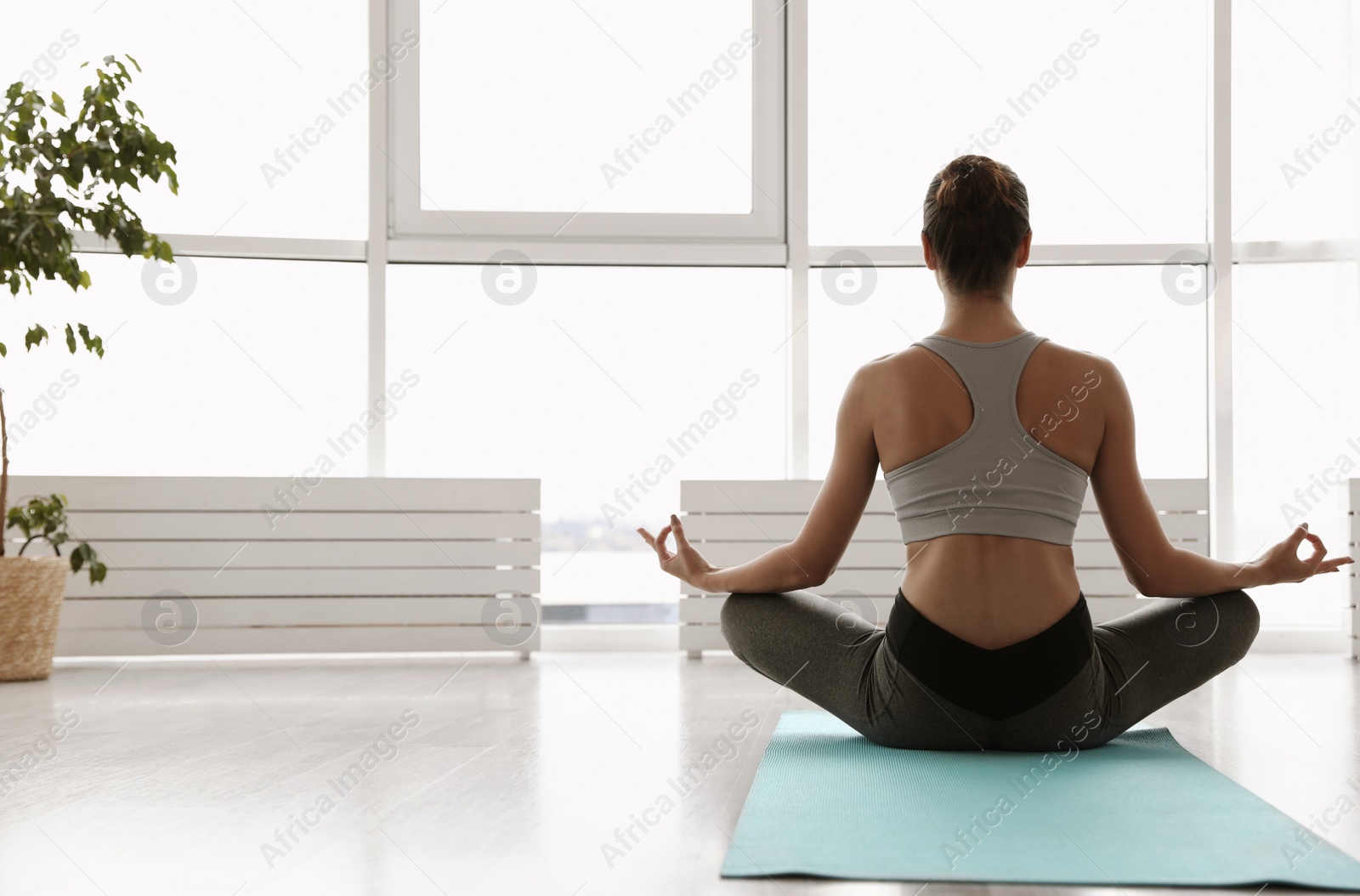 Photo of Young woman practicing easy asana in yoga studio, back view. Sukhasana pose