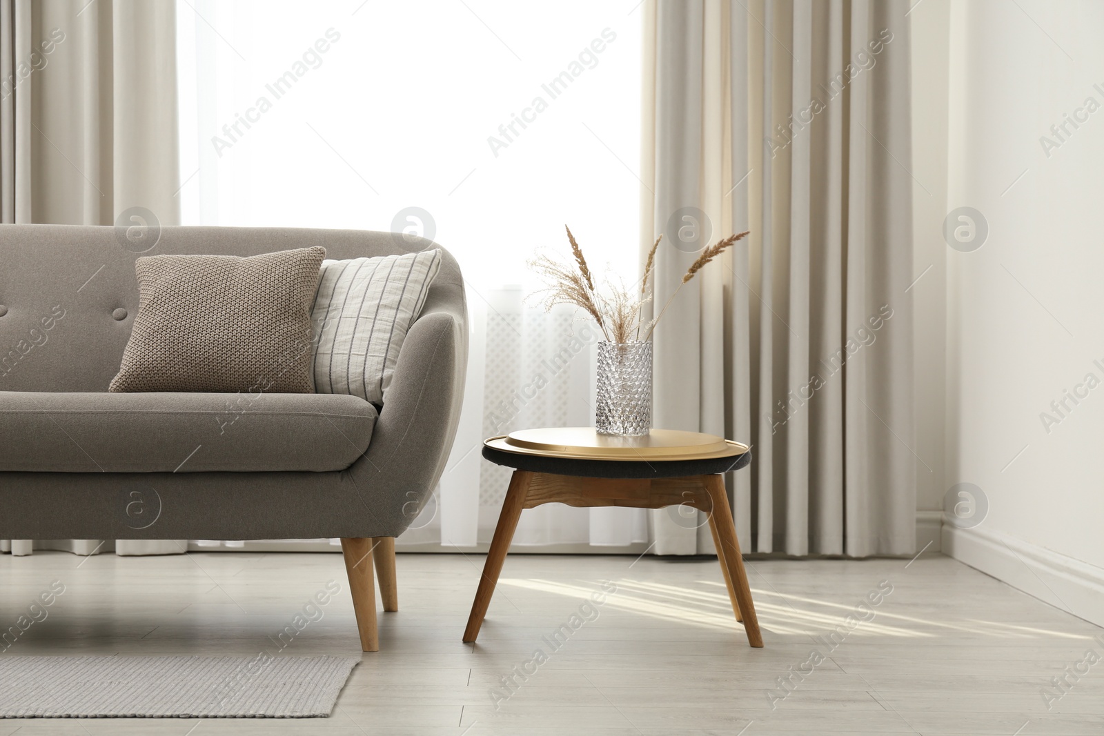 Photo of Grey sofa with pillows near window in stylish living room interior