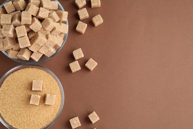 Photo of Granulated brown sugar and cubes on color background, flat lay. Space for text