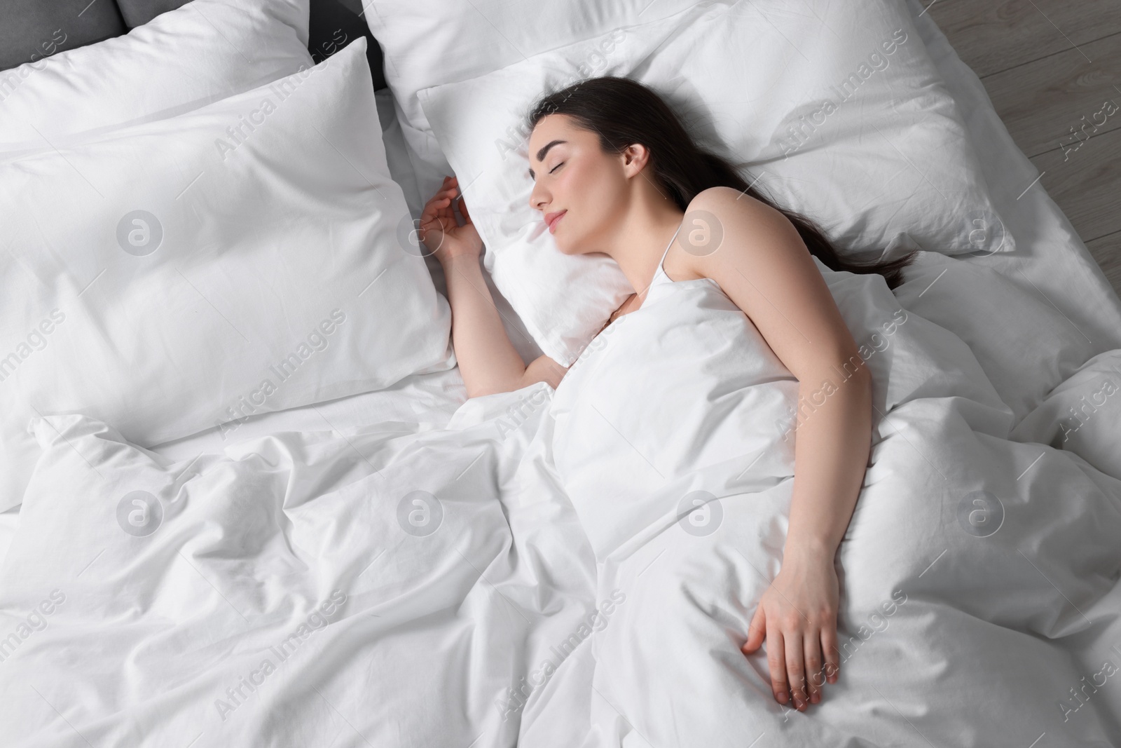 Photo of Beautiful young woman sleeping in soft bed, above view