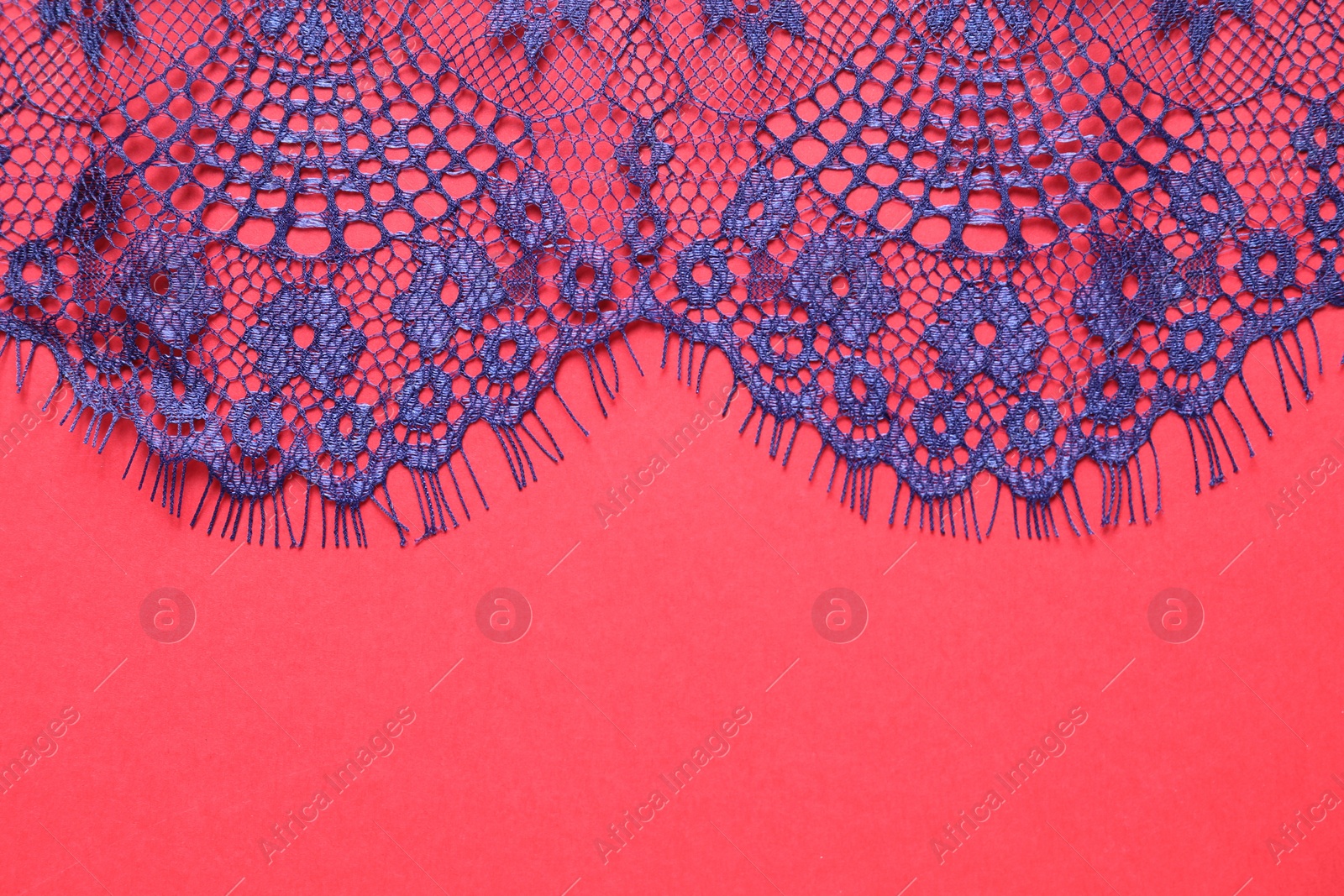 Photo of Blue lace on red background, top view. Space for text