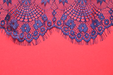 Blue lace on red background, top view. Space for text