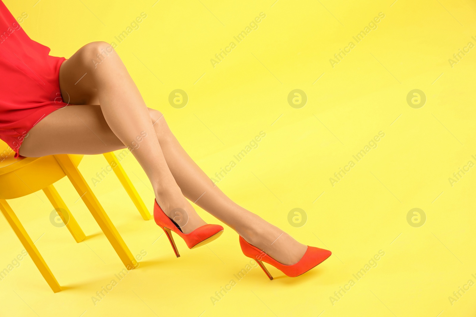 Photo of Woman wearing tights and stylish red shoes on yellow background, closeup