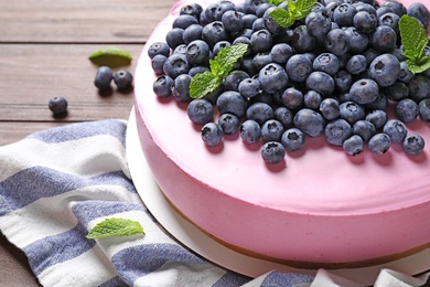 Photo of Tasty blueberry cake and napkin on wooden table, closeup. Space for text