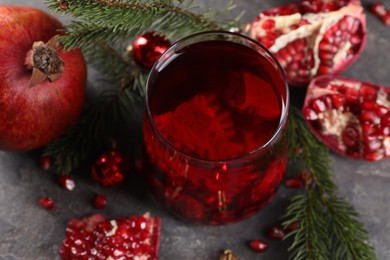 Photo of Aromatic Sangria drink in glass, Christmas decor and pomegranate grains on grey table, above view