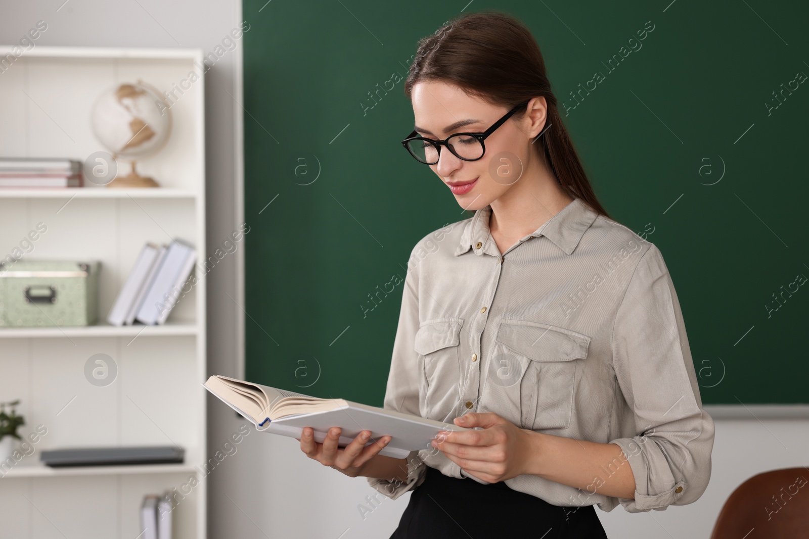 Photo of Beautiful young teacher reading book in classroom