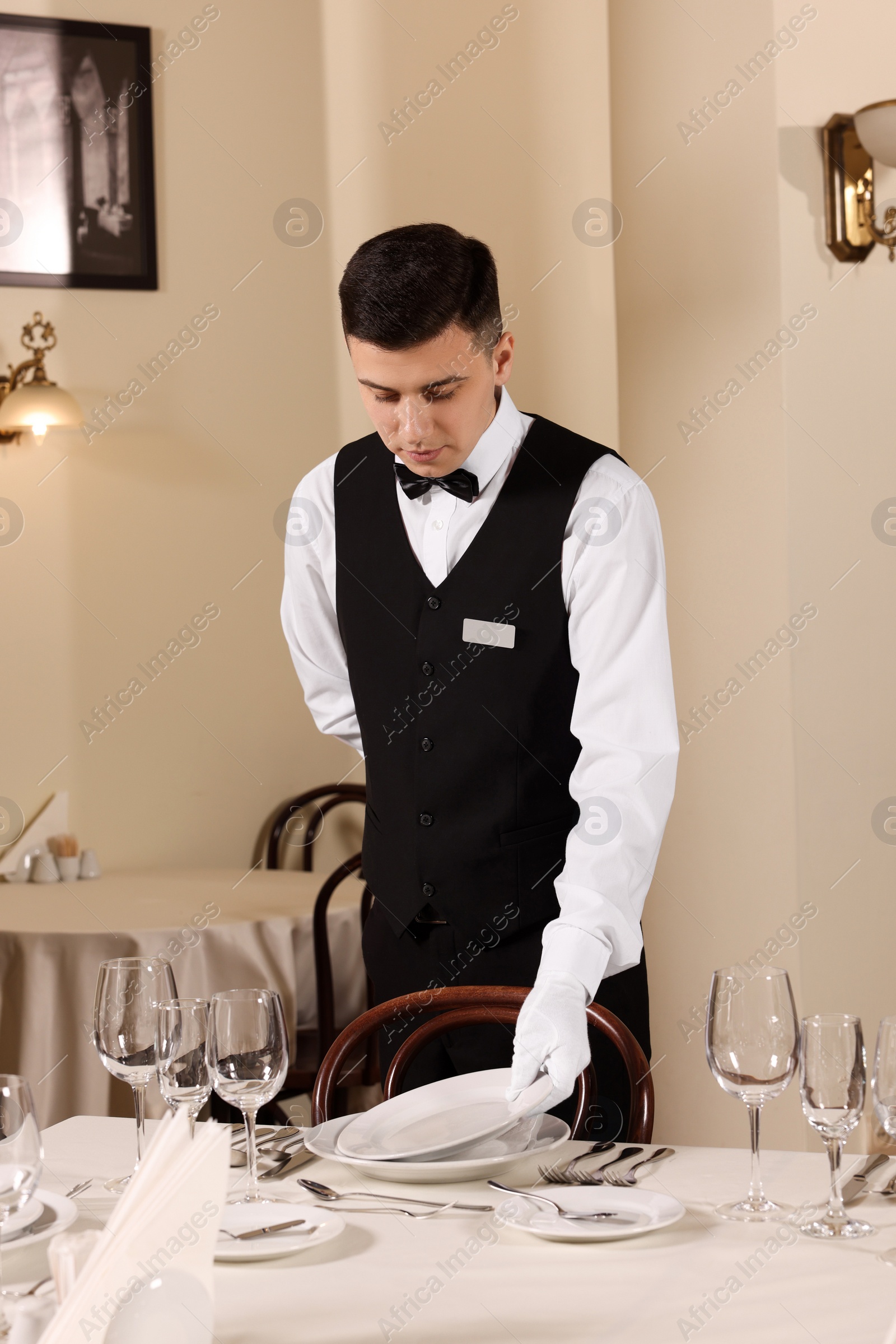 Photo of Man setting table in restaurant. Professional butler courses