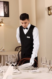 Man setting table in restaurant. Professional butler courses