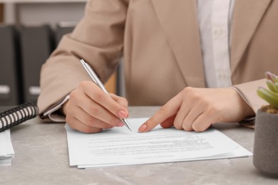 Photo of Woman signing document at table, closeup view