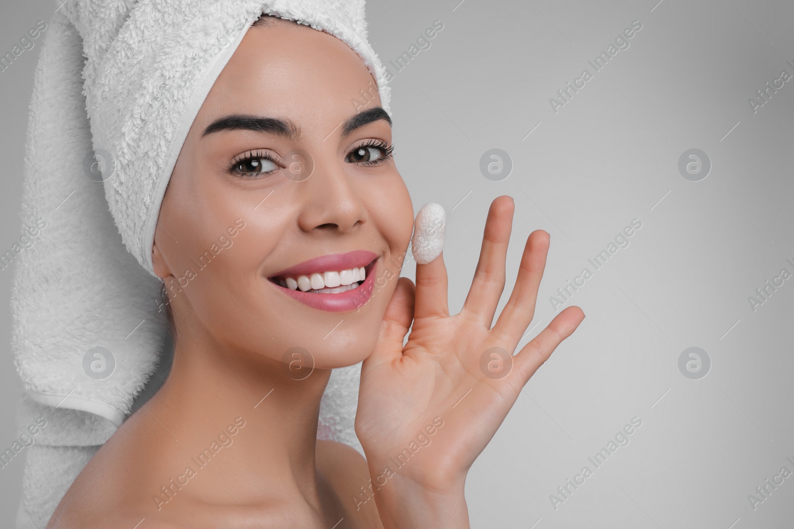 Photo of Woman using silkworm cocoon in skin care routine on light grey background. Space for text