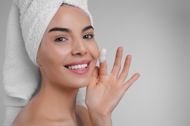 Photo of Woman using silkworm cocoon in skin care routine on light grey background. Space for text