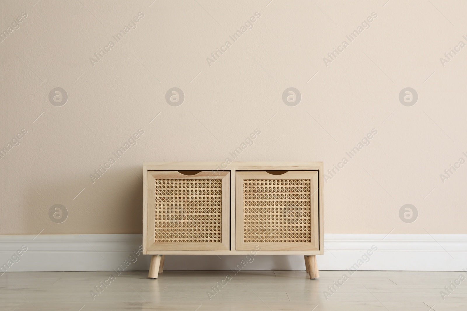 Photo of Wooden chest of drawers near beige wall indoors