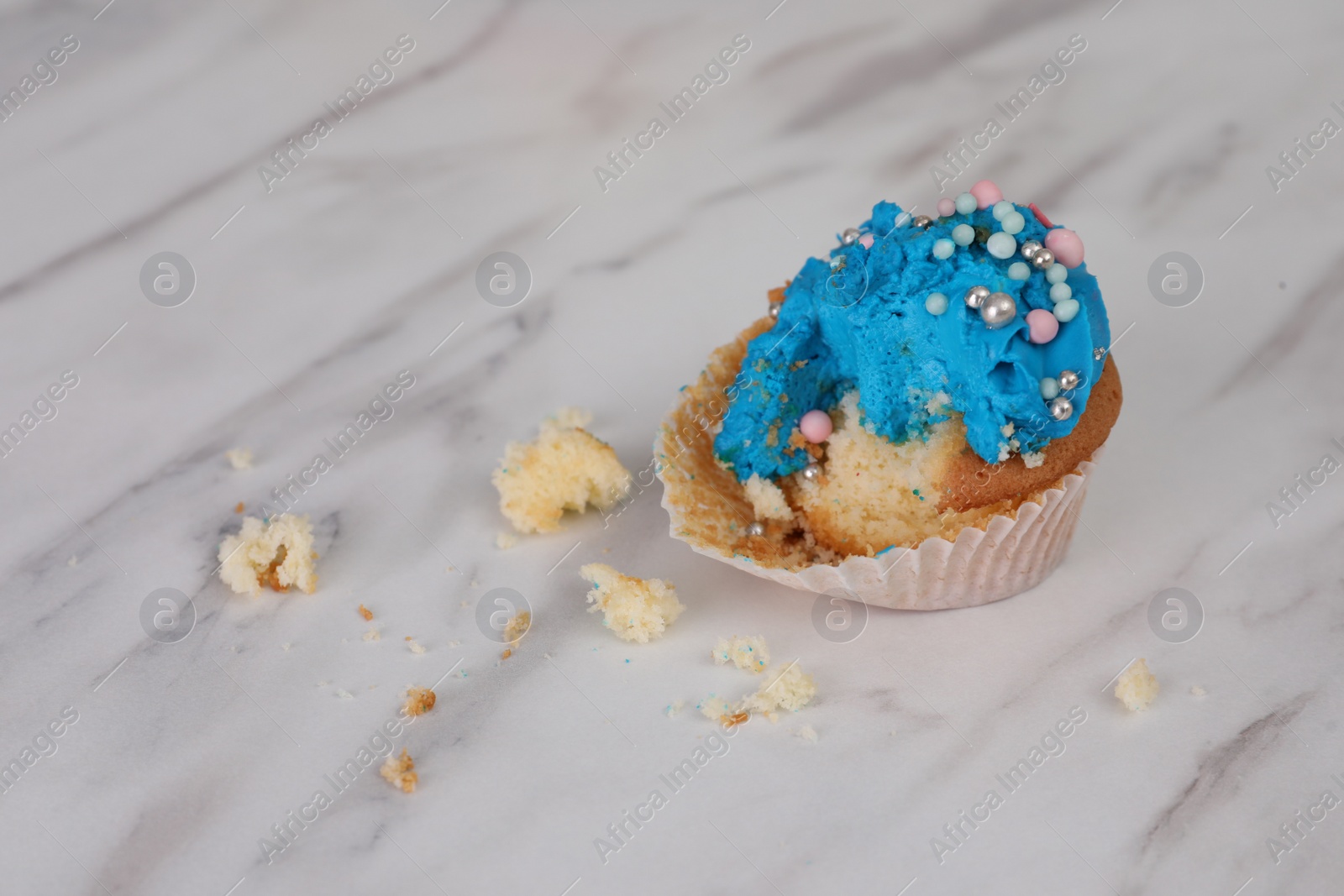 Photo of Failed cupcake with cream on light table. Troubles happen