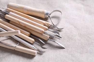 Photo of Set of different clay crafting tools on grey fabric, closeup. Space for text